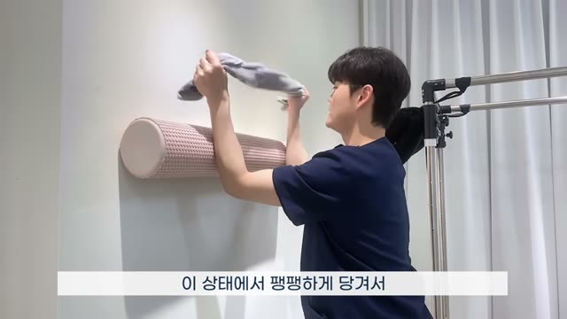 수건을 팽팽하게 유지하며 팔을 위로 뻗어 올린 자세