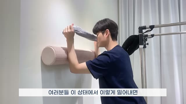 벽 앞에서 수건을 잡고 팔꿈치를 굽혀 내린 W 자세